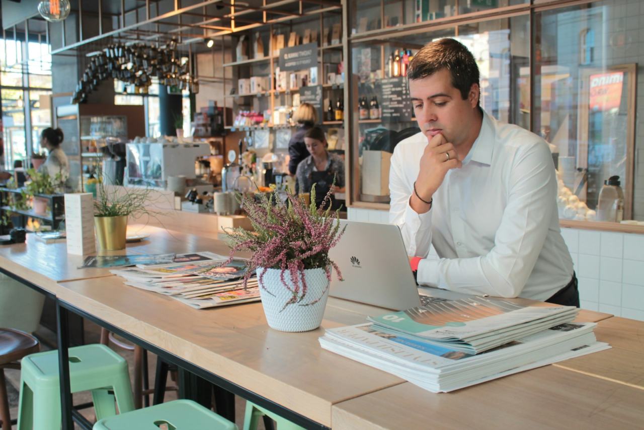Business owner checking a laptop at the counter of a busy cafe