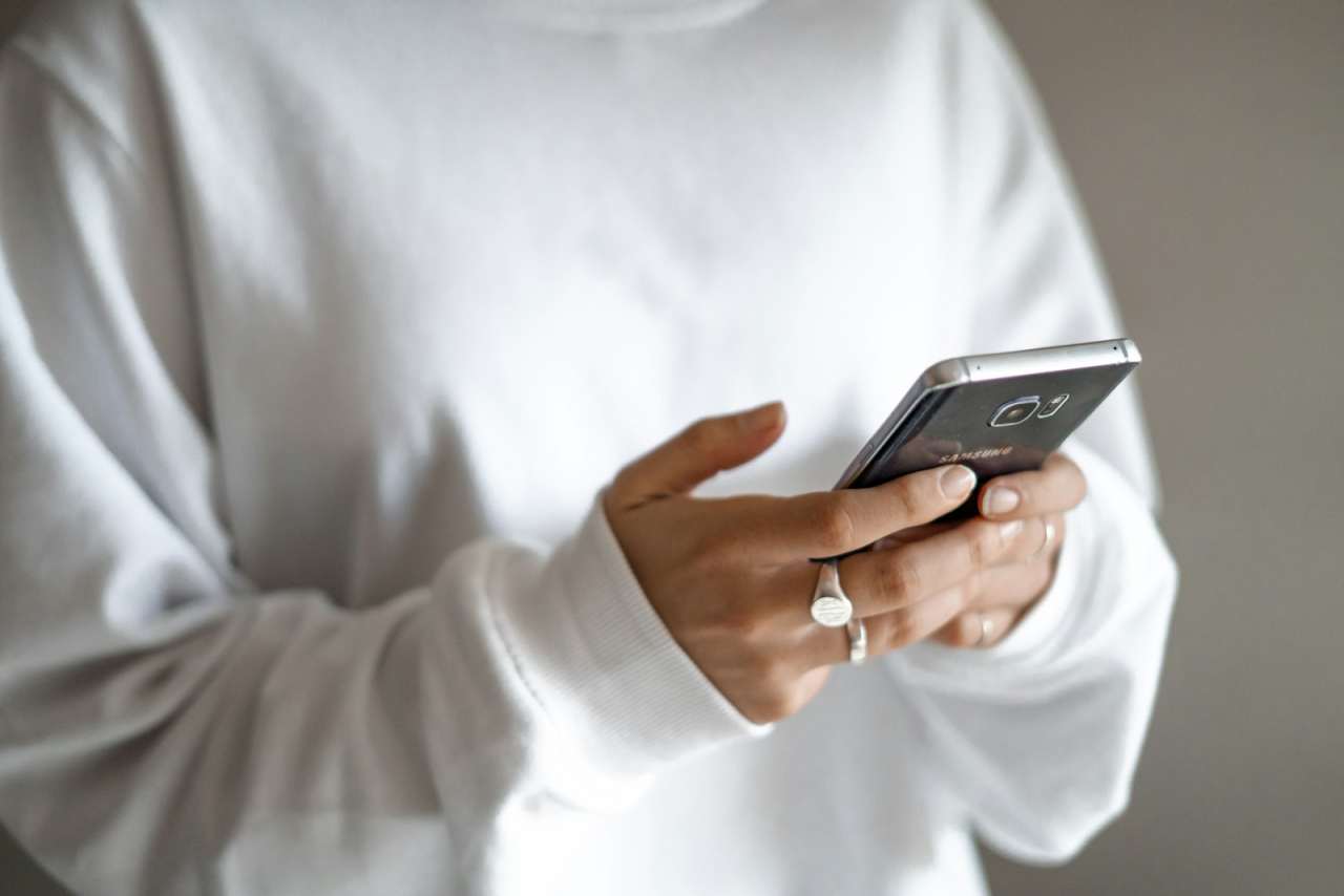 Person in a white jumper reading a message on a smartphone