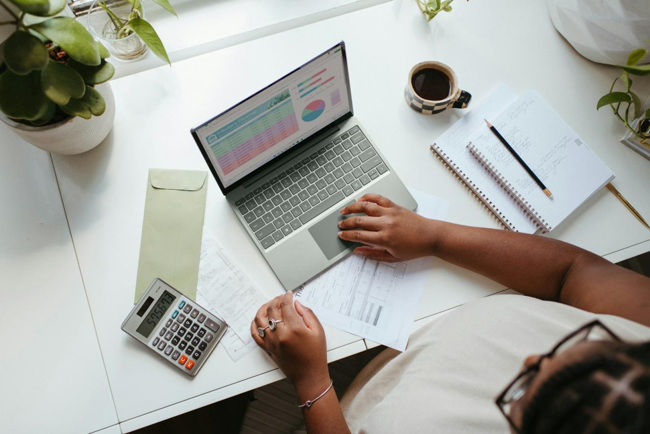 Business owner working through costs on a laptop with a calculator