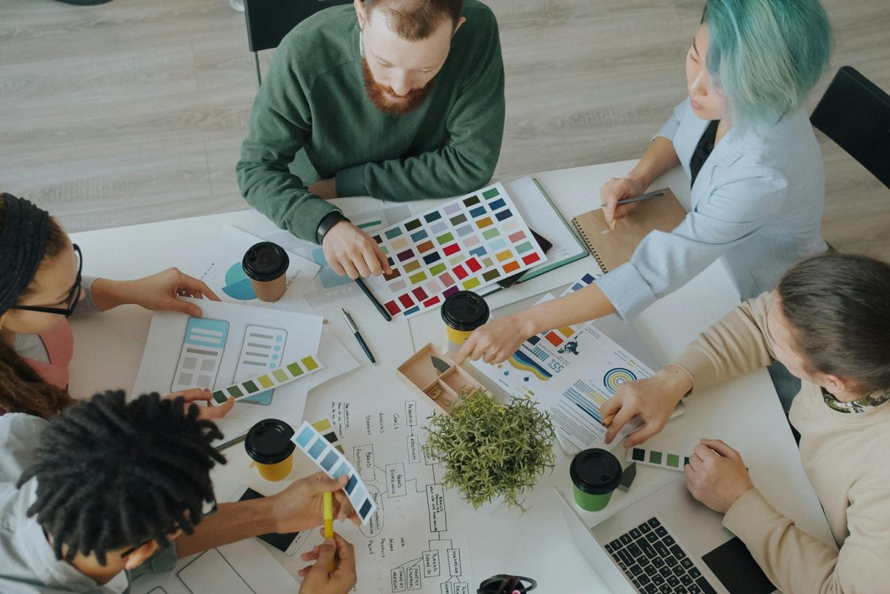 Design team planning a website around a table with colour swatches and wireframes