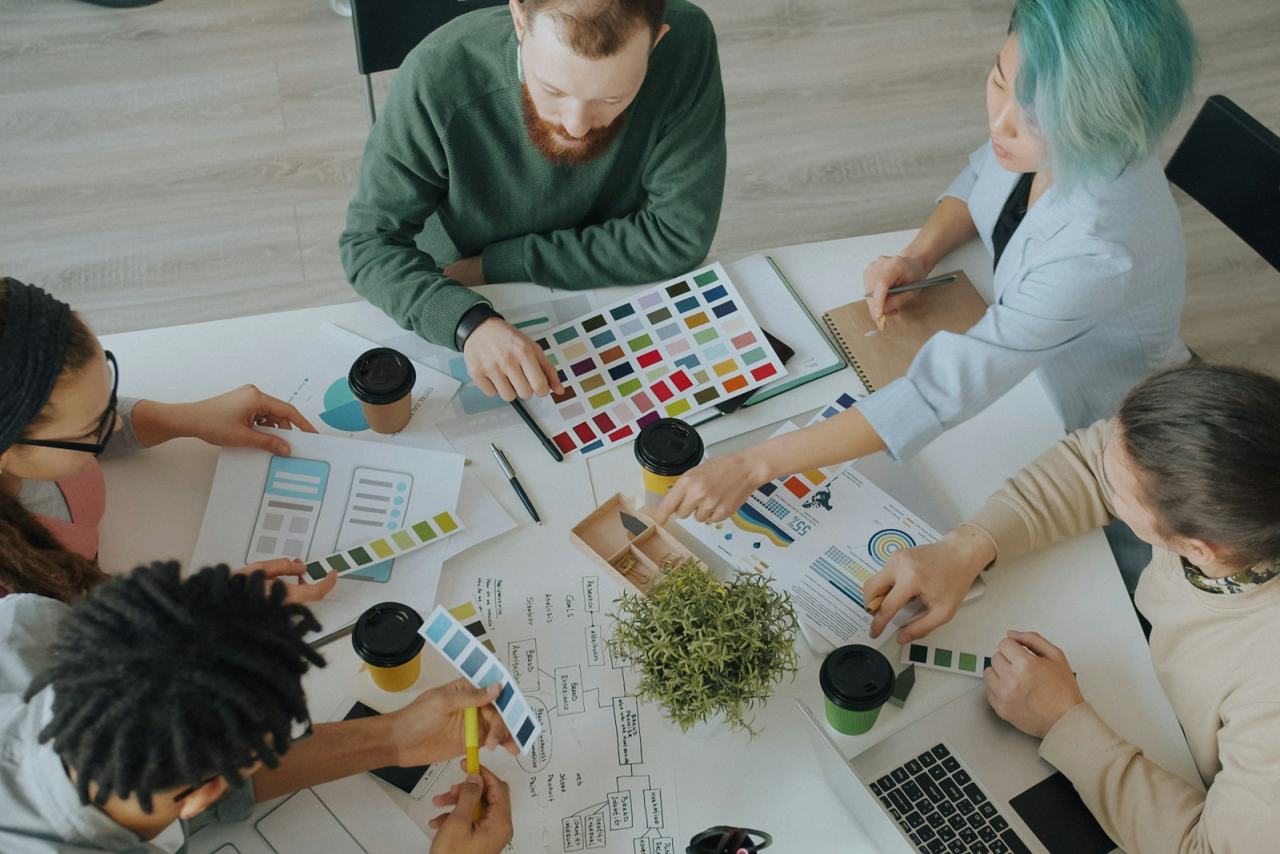 Design team planning a website around a table with colour swatches and wireframes